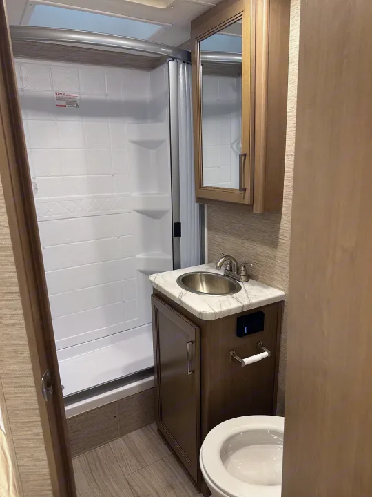 Modern RV rental bathroom showcasing a compact shower, vanity with sink, and toilet for comfortable travels.. Thor Coleman 2021
