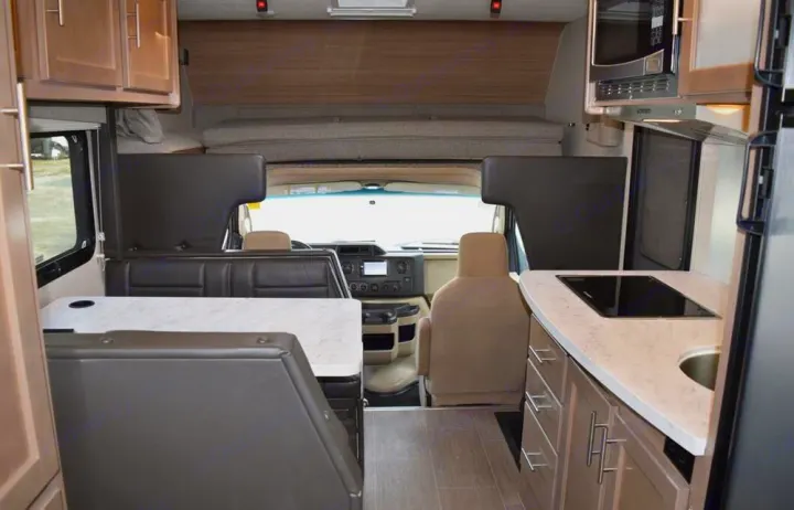 Spacious rv rental interior: dinette, kitchen (stovetop/sink, microwave), cab-over bunk, and cockpit visible upfront.. Adventurer Adventurer 2020