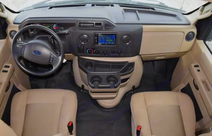 RV rental interior: A spacious van cockpit featuring a Ford steering wheel, dashboard, infotainment, cup holders, and front seats.. Adventurer Adventurer 2020