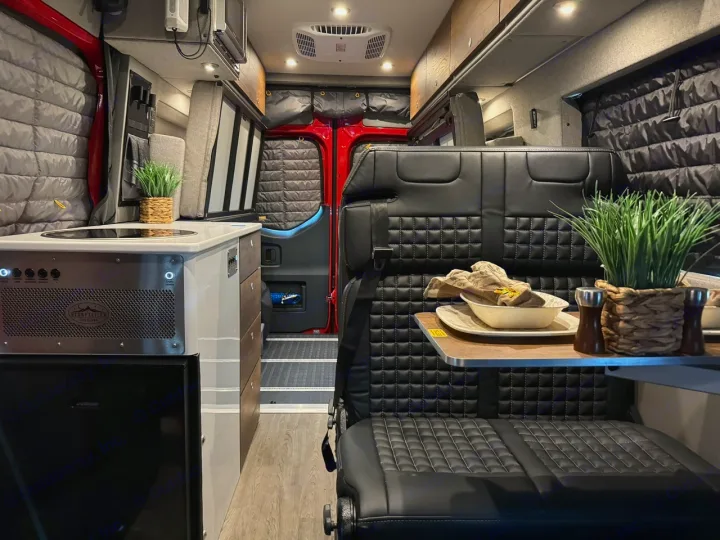 Explore this RV rental's modern kitchen with cooktop & fridge, comfy black leather dining seats, and quilted window covers.. Storyteller Overland Beast Mode AWD 2024