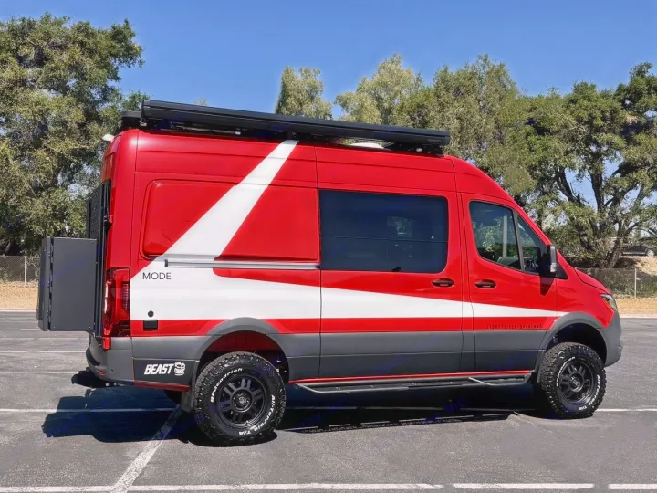 Vibrant red & white Storyteller Overland camper van ready for your next rv rental adventure. Parked outdoors with all-terrain tires.. Storyteller Overland Beast Mode AWD 2024