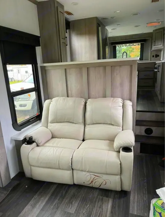 Spacious RV rental interior featuring a cream reclining sofa with cup holders, a modern kitchen, and comfortable living area.. Heartland RVs Big Country 2021