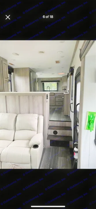Spacious RV rental interior featuring a cream sofa, modern kitchen, and steps. Includes safety gear like a fire extinguisher.. Heartland RVs Big Country 2021