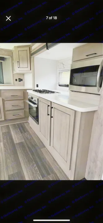Step inside this sleek RV rental kitchen. Features modern cabinets, white countertops, oven, and microwave for home-like comfort.. Heartland RVs Big Country 2021