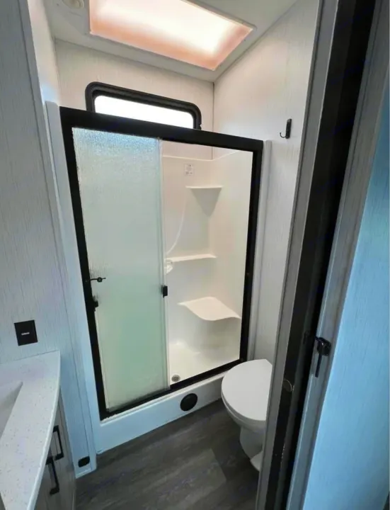 Modern RV rental bathroom: walk-in shower with seat, toilet, and vanity. Bright space with skylight for comfort.. Heartland RVs Big Country 2021