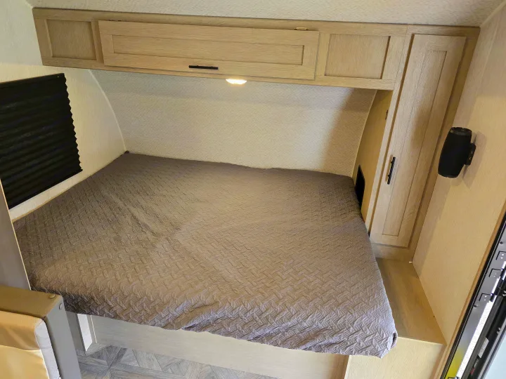 Cozy RV rental bedroom with light wood cabinets, a grey bedspread, and a black window blind.. Forest River Salem FSX 2024