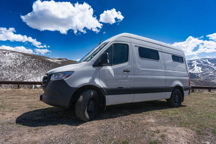 Scenic rv rental: White camper van on a mountain road with snow-dusted hills & blue sky.. Mercedes-Benz Sprinter-Loaded 2022