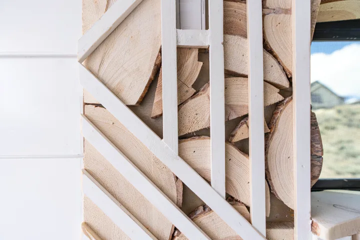 An RV rental's unique wall: white crisscross slats over natural wood slices. A window and control panel are visible.. Mercedes-Benz Sprinter-Loaded 2022