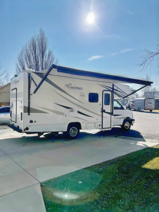 Bright day for an rv rental! A white Coachmen Freelander motorhome with awning extended, parked on a sunny driveway.. Coachmen Freelander 2020