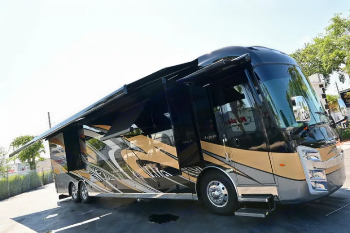 A large, black and gold luxury RV is parked with slide-outs and awnings extended, ideal for your next RV rental adventure.. Entegra Coach Aspire 2019