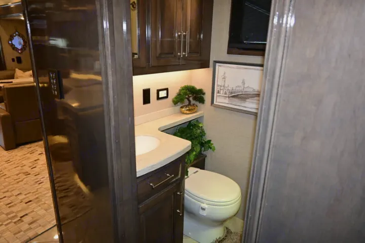 RV rental luxury: a stylish bathroom with a compact vanity, sink, toilet, and elegant decor inside a modern motorhome.. Entegra Coach Aspire 2019