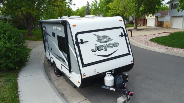 White & gray Jayco travel trailer parked on a suburban street, ready for your next RV rental adventure.. Jayco Jay Feather 2016