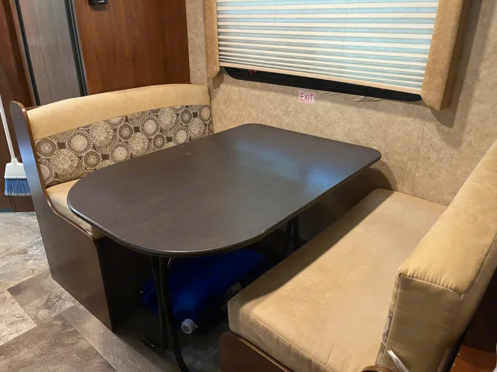 RV rental interior: A practical dinette area with a dark table, patterned benches, and an emergency exit window.. Jayco Jay Feather 2016