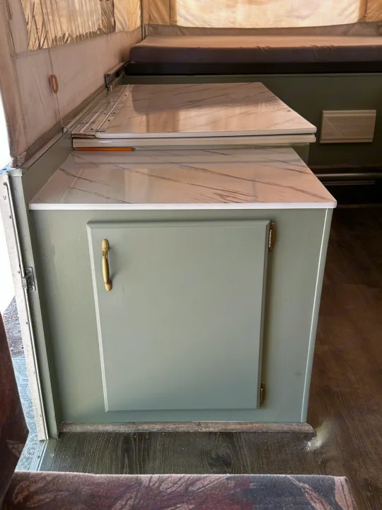 RV rental: Renovated light green cabinet with brass handle, marble counters, and bedding in a pop-up camper interior.. Jayco Eagle 2001