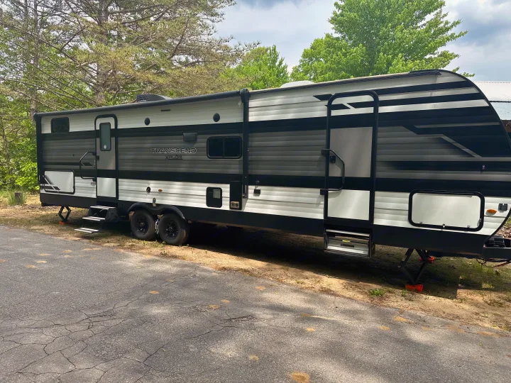 RV rental: A black, gray, and white Transcend Xplor travel trailer is parked on a dirt lot next to asphalt.. Grand Design Transcend Xplor 2022