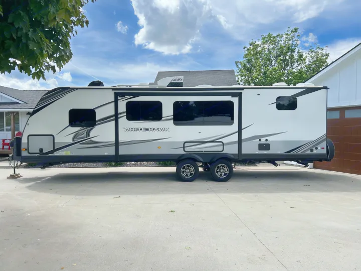 White Jayco White Hawk RV rental, a sleek travel trailer with grey accents, parked on a concrete driveway.. Jayco White Hawk 2022