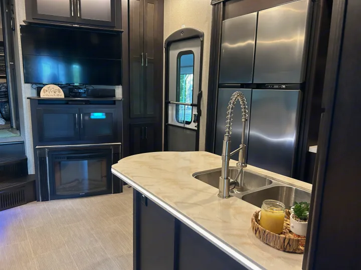 Modern RV rental interior featuring a full kitchen with an island, living area, fireplace, and large TV.. Raptor Raptor 2017