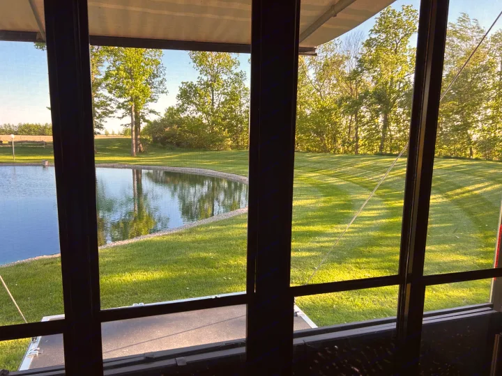 Scenic view from an RV rental: a calm pond with reflections, a neatly striped lawn, and lush green trees.. Raptor Raptor 2017