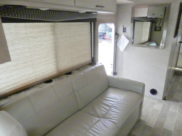 Relax in this RV rental's modern living area featuring a light gray sofa, large window, and durable flooring.. Thor Chateau 2021