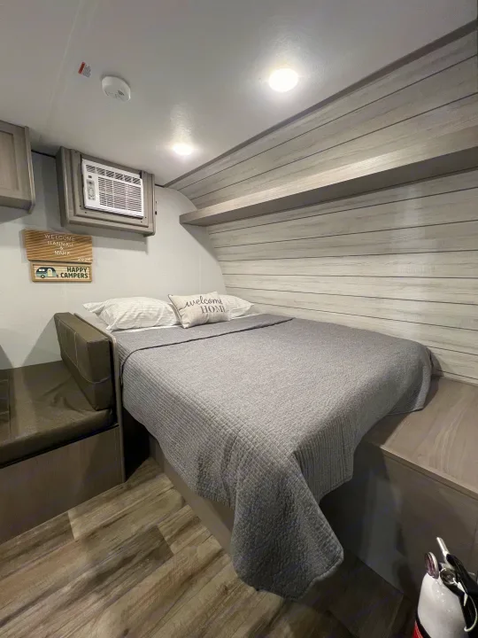 Experience comfortable living in this RV rental bedroom with a cozy bed, AC, and stylish wood-look interior.. Coleman Lantern 17B 2024