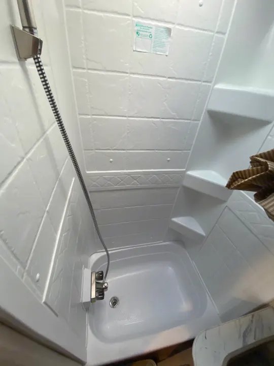 RV rental shower stall with white molded walls, handheld shower, small basin, and built-in shelves.. Starcraft Launch Outfitter Extreme 2018