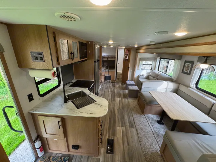 Step inside this modern rv rental. View of kitchen, dining booth, and living area, complete with wood-look floors.. Prime Time Avenger 2022