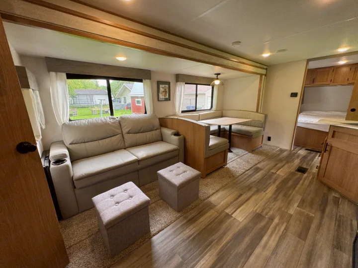 Spacious RV rental interior featuring a cozy sofa, U-shaped dinette, and stylish wood-look flooring.. Prime Time Avenger 2022