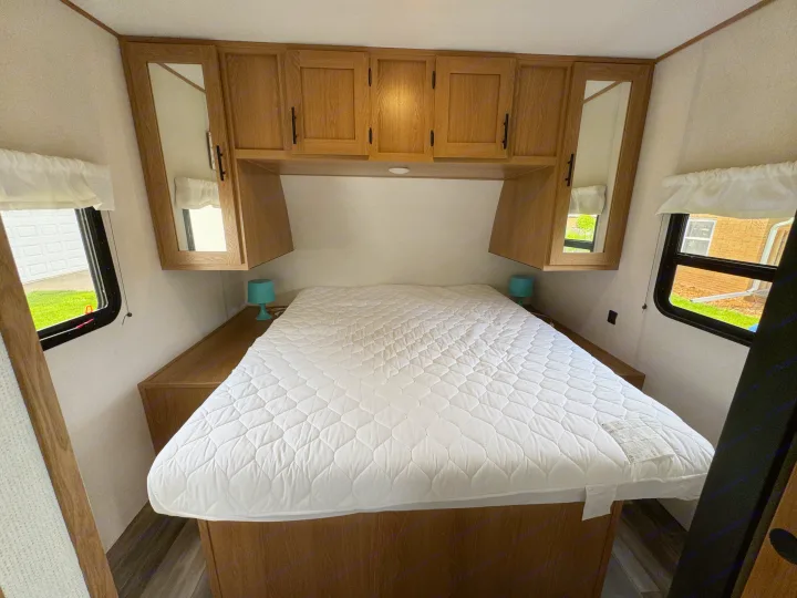 Clean RV rental bedroom with a queen bed, overhead cabinets with mirrors, and side windows for natural light.. Prime Time Avenger 2022