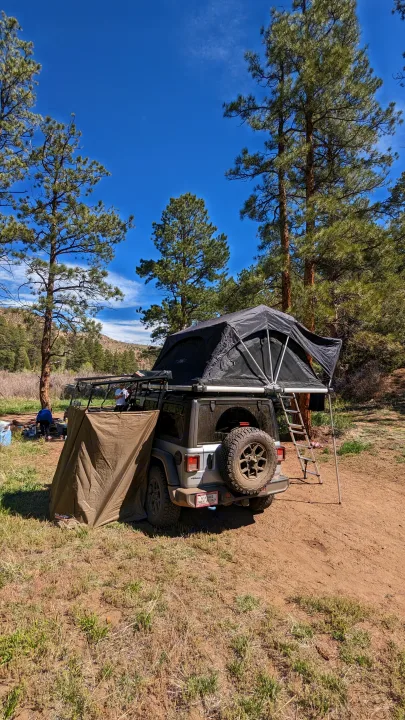 An RV rental alternative: a Jeep with rooftop tent & privacy awning set up for scenic off-road camping.. Jeep Wrangler 2024