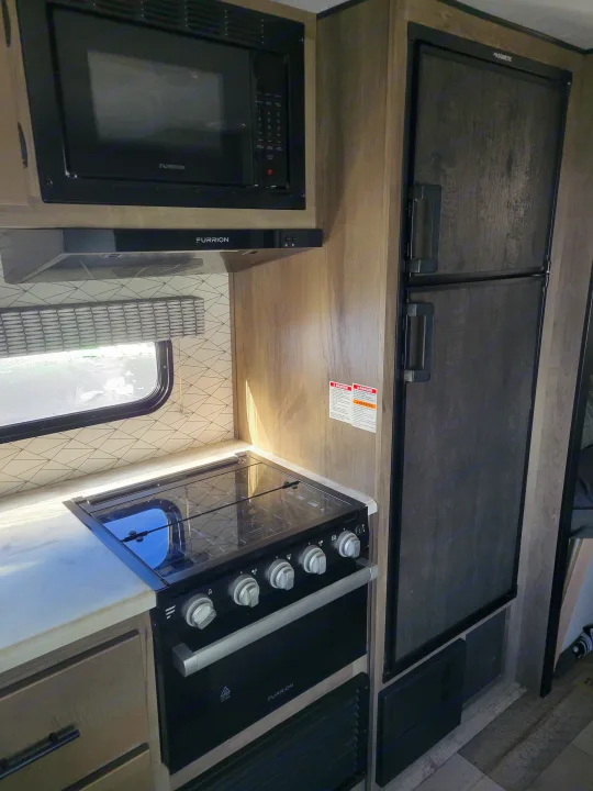 RV rental kitchen showing Furrion microwave, oven, range hood & Dometic fridge. Perfect for road trip meals.. KZ Confluence 2022