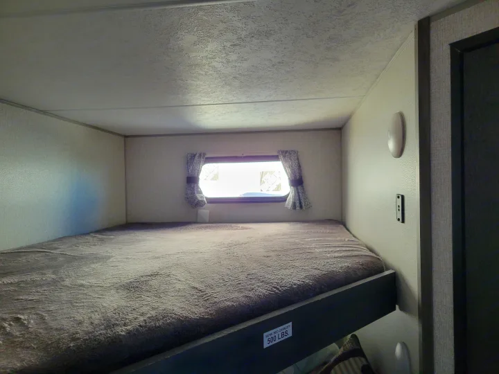 This RV rental features a cozy bunk bed with a window, ideal for sleeping. The top bunk has a 500 lbs capacity.. KZ Confluence 2022