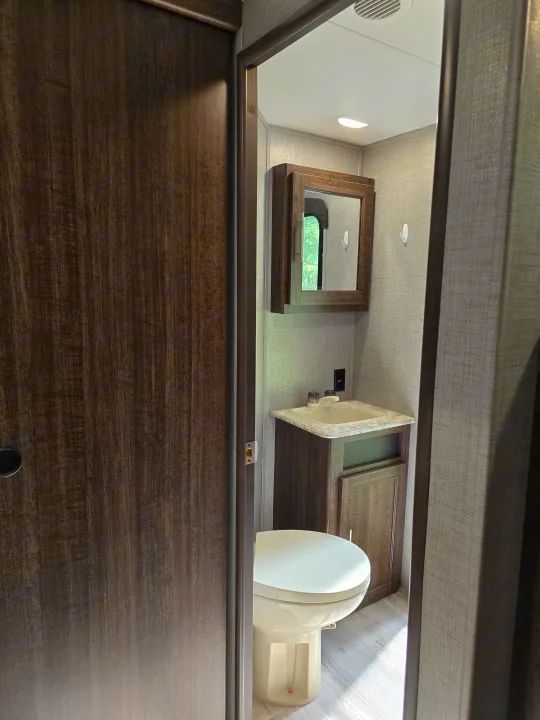 Step into this compact RV rental bathroom featuring a toilet, sink, and mirrored cabinet. Bright and functional.. Crossroads RV Zinger 2018