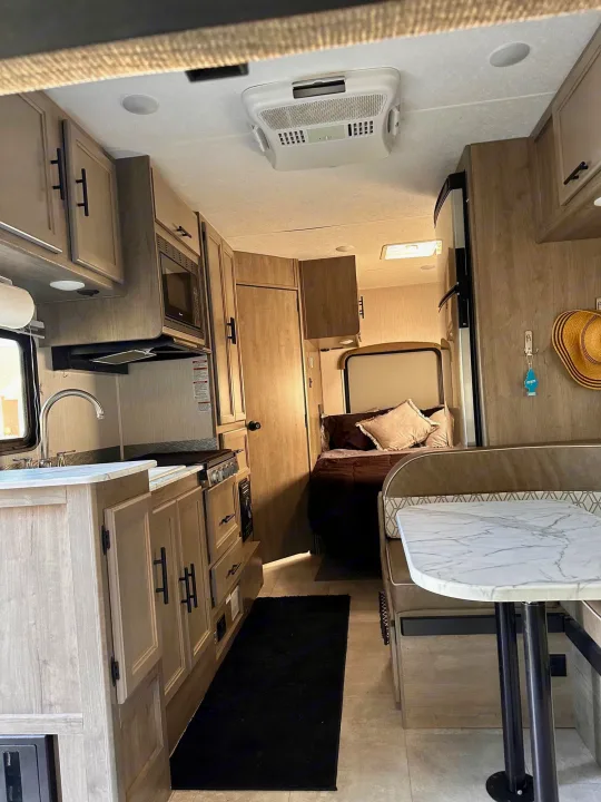 Inside this modern rv rental, find a light-toned kitchen, dinette, and cozy bed, perfect for travel comfort.. Coachmen Freelander 2020