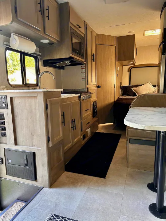 This RV rental interior showcases a modern kitchen, cozy dinette, and comfortable bed area, ideal for travel.. Coachmen Freelander 2020