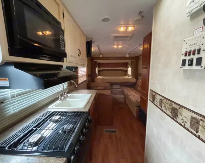 Spacious RV rental interior: Full kitchen (stove, microwave, sink) & comfortable bed/lounge area.. Keystone RV Outback 2010