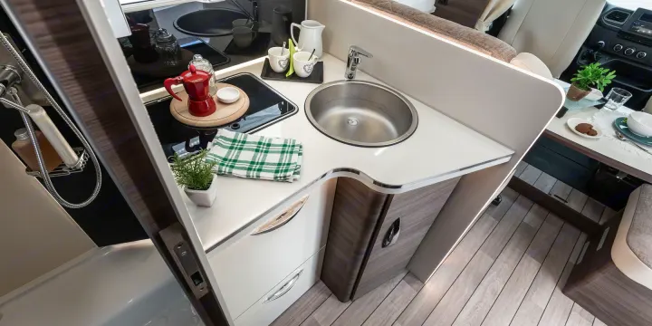 Well-appointed RV rental interior: kitchen with sink, stove, and dining area, ready for comfortable travels.. MCLOUIS YEARLING 89 2024