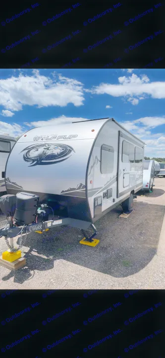 This sleek grey and white Wolf Pup travel trailer is perfect for RV rental adventures. Parked on gravel, this camper awaits its next journey.. Forest River Cherokee Wolf Pup Black Label 2022