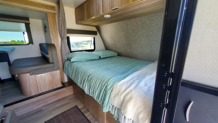 Cozy RV rental interior with a comfortable bed, dinette, and bright windows offering a view of the outdoors.. Winnebago Minnie Winnie 2021