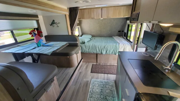 Spacious rv rental interior featuring a cozy bedroom, dinette, and kitchenette. Perfect for travel adventures!. Winnebago Minnie Winnie 2021