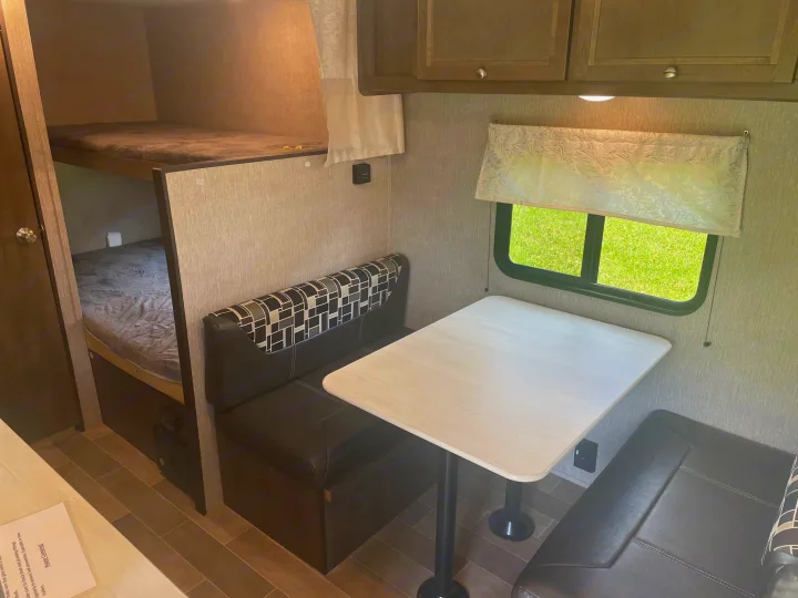 Step inside this RV rental, showcasing a comfortable dinette and bunk beds, perfect for family adventures.. Coleman 17FQ 2019