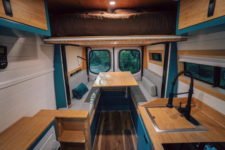 This RV rental's modern interior showcases a kitchen, dining nook, and elevated bed. Ideal for van life exploration.. Mercedes-Benz Sprinter 2024