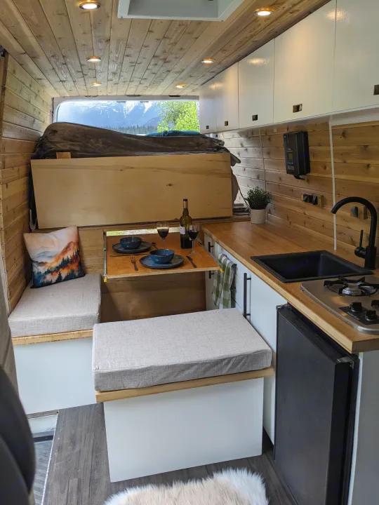 An RV rental's inviting wood-paneled interior features a well-equipped kitchenette, cozy dinette, and stunning mountain views.. Dodge Sprinter Van 2007