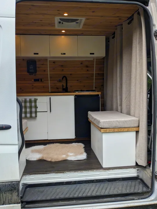 RV rental: Step inside this modern camper van featuring a compact kitchen, bench, and warm wood-paneled interior.. Dodge Sprinter Van 2007
