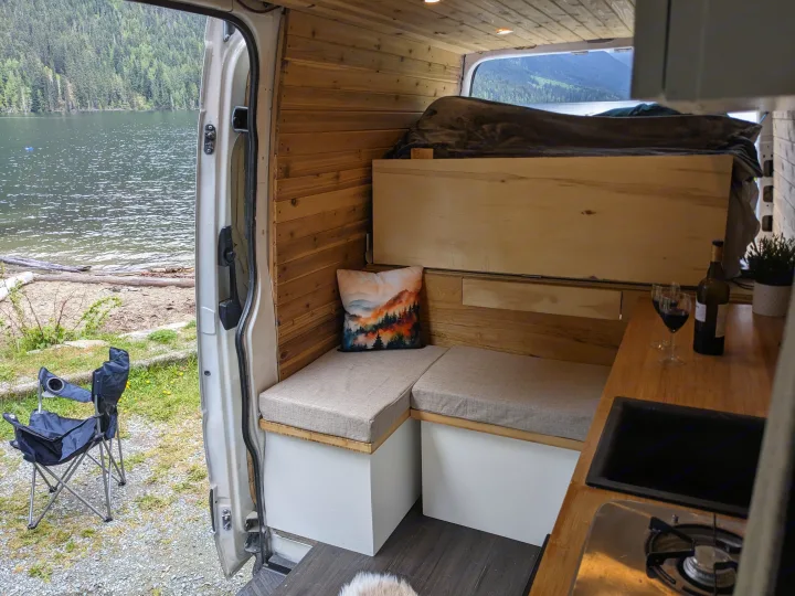 Enjoying the scenic lake view from a custom RV rental. Inside features a cozy bed, seating, and kitchen area.. Dodge Sprinter Van 2007