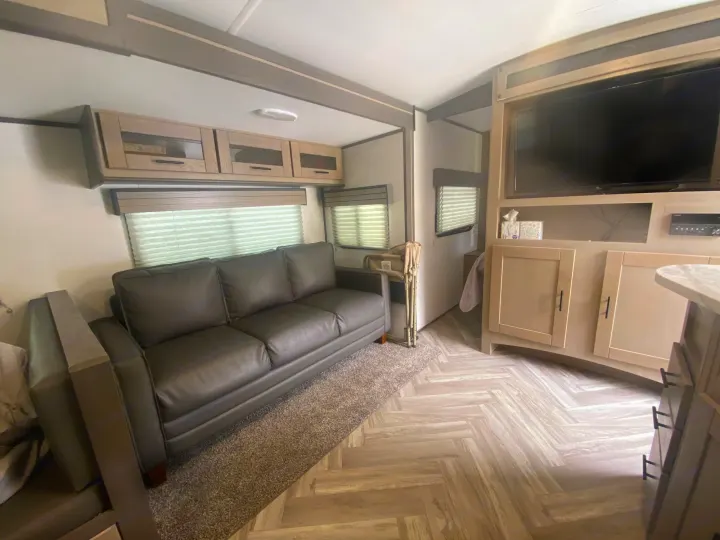 Inviting rv rental interior: main living area with a comfy gray sofa, TV, and sleek light wood cabinetry.. Cruiser RV Shadow Cruiser 2021