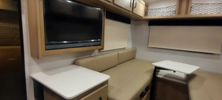 Inside a modern RV rental featuring a TV, comfortable sofa seating, and dual tables, highlighting its compact living area.. Forest River Rockwood Geo Pro 2024