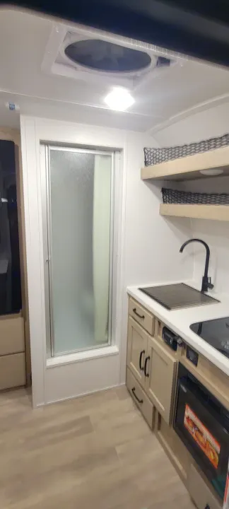 RV rental: Clean, modern interior with kitchen (sink, stove, microwave) and a compact shower stall on light wood-look flooring.. Forest River Rockwood Geo Pro 2024