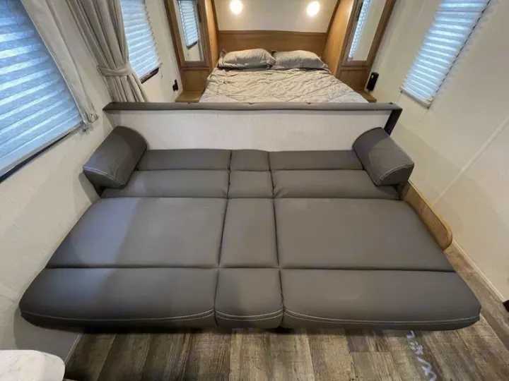 Inside an RV rental: a plush bed and a convertible sofa-bed, maximizing sleeping space for guests.. Forest River Cherokee Grey Wolf Special Edition 2022