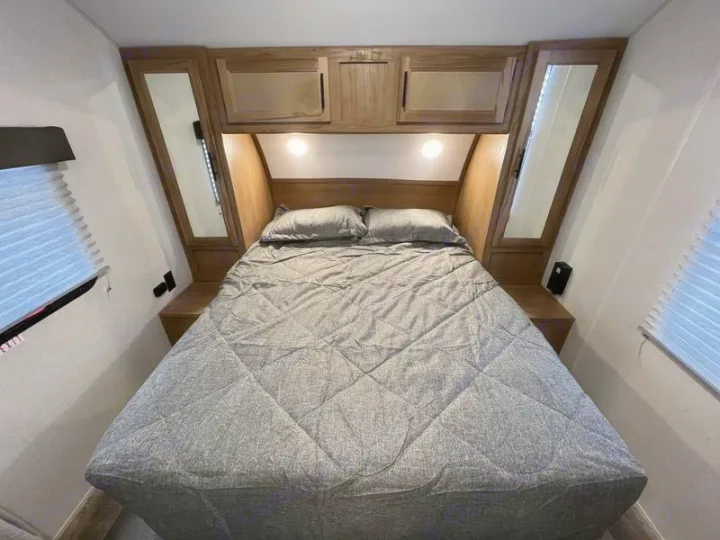 Cozy RV rental bedroom with gray bedding, overhead storage, and mirrored closets.. Forest River Cherokee Grey Wolf Special Edition 2022