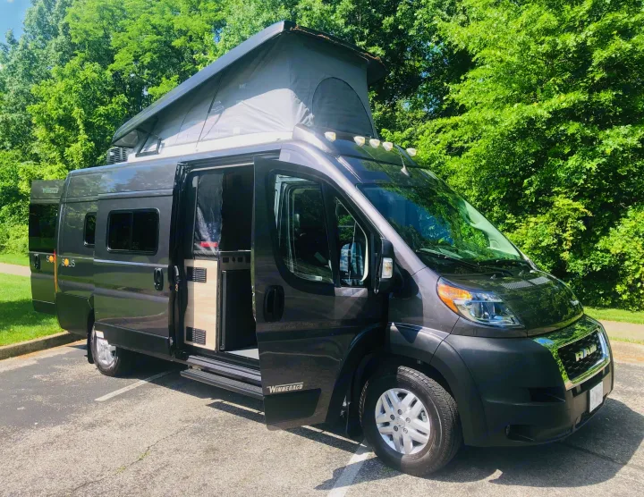 Gray pop-top camper van RV rental, Winnebago Solis, with open doors parked outdoors.. Winnebago Solis 2023